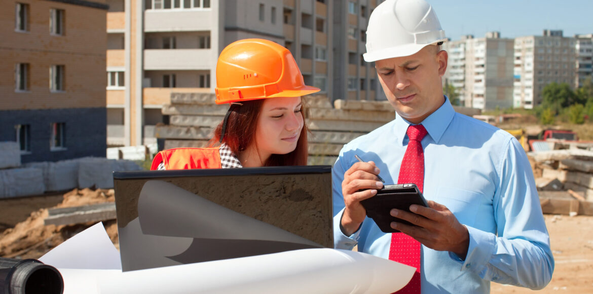 Two architects in front of building site Two architects wearing protective helmet standing in front of building site